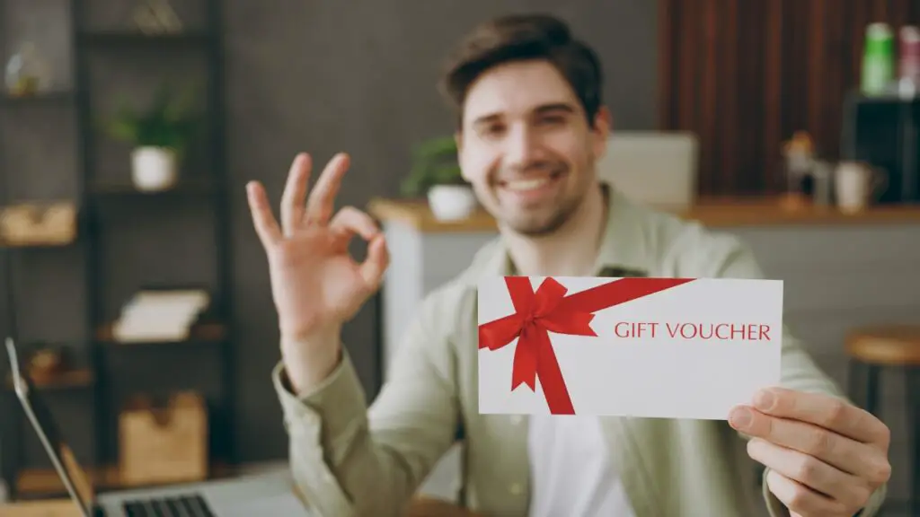 Man holding a gift voucher and making an OK hand gesture