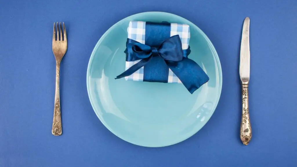 Small wrapped gift on a plate set with fork and knife