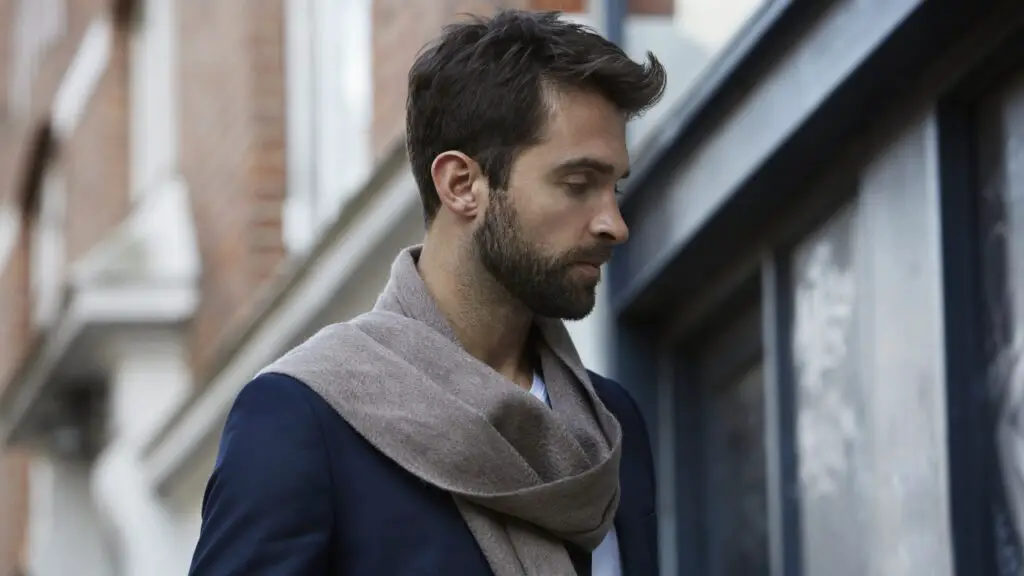Man in a coat and scarf standing outside near a storefront