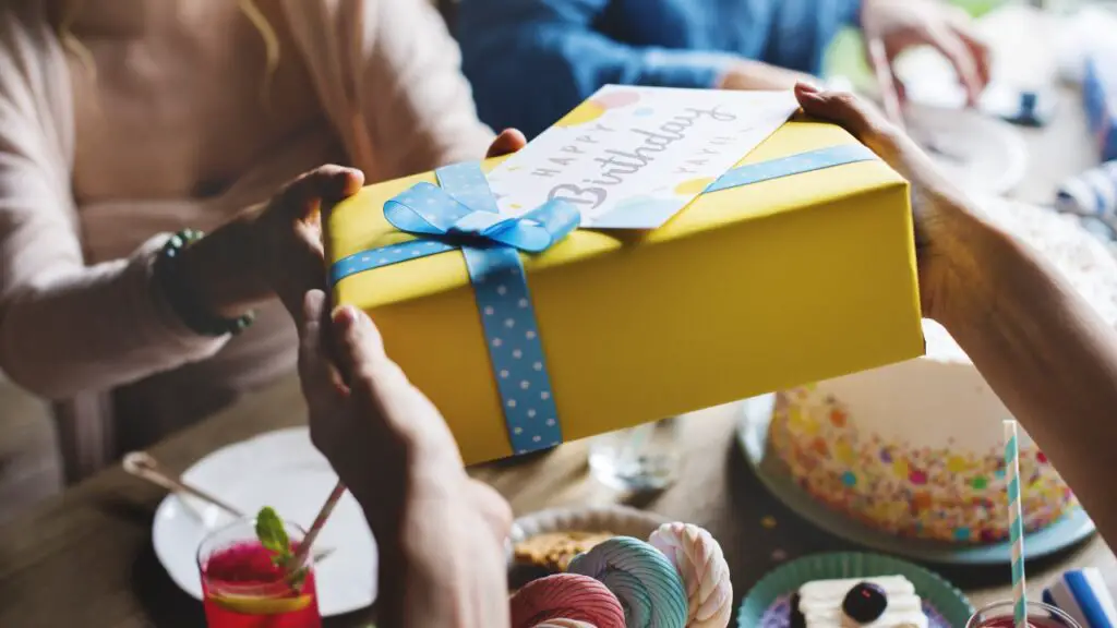 Person handing over a yellow birthday gift box with a card during a 40th birthday celebration
